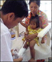 A Cambodian CSPO clinician works on a cast for a pediatric patient.