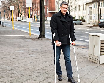 patient with crutches on sidewalk