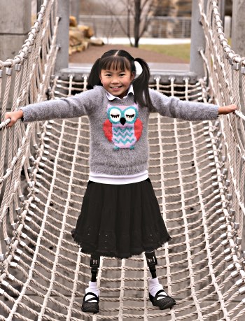 Child with bilateral prostheses on rope bridge