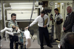 Technician Mario Ortiz (left) demonstrates vacuum-forming plastic over a custom leg mold as Randy McFarland, CPO, owner of Sunny Hills Orthopedic Services, narrates. Members of the Fullerton Chamber of Commerce, along with Kay Miller, city economic development manager, and Mayor Don Bankhead, look on.