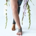 Beautiful imperfection. Cropped view of the disabled tattooed woman with prothesis leg standing with flowers at the studio with white background