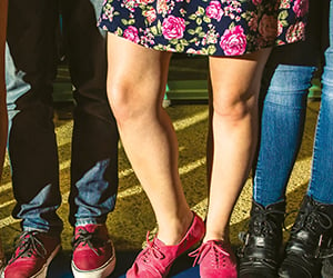 Young Adult legs and feet standing together on blue curb