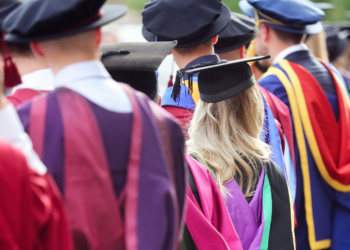 Graduates at university graduation  ceremony wearing mortarboard and gown
